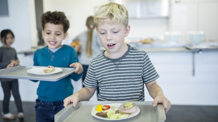 Pupils carrying trays in school canteen - The Deeping