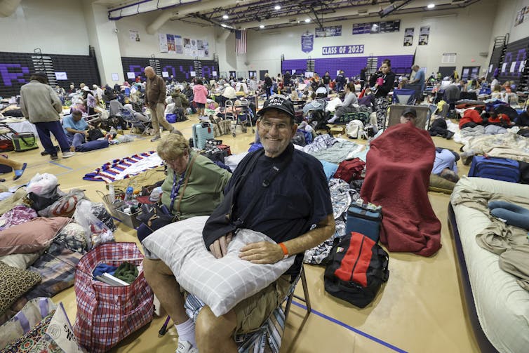 image - The Deeping A man smiles at the camera from a crowded school gym.