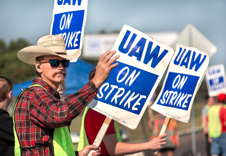 file-20250407-62-8i6zv7 - The Deeping Man in a cowboy hat holding a sign saying 'UAW on strike'.